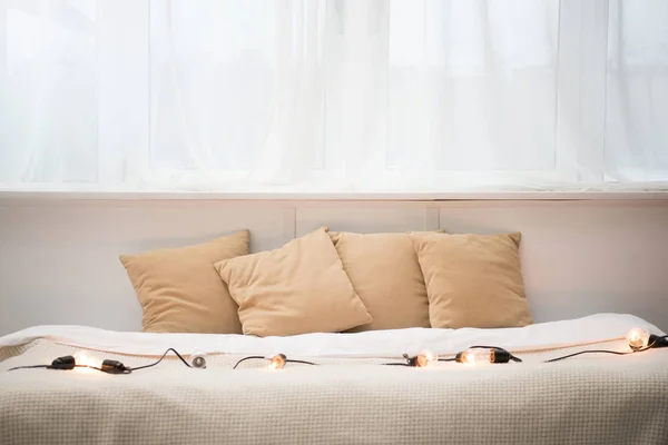 Пустая Кровать Коричневыми Подушками Белым Одеялом Праздничными Огнями — стоковое фото