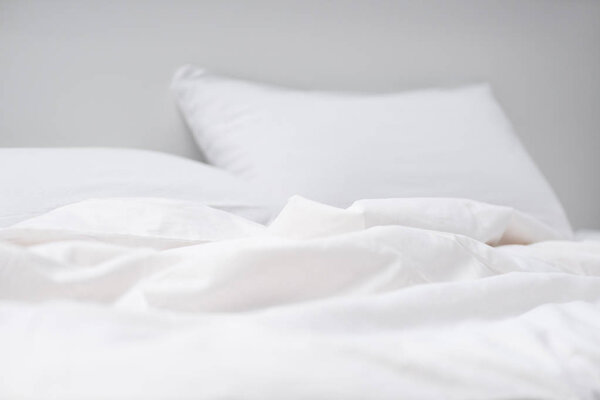 selective focus of empty bed with white pillows and blanket 