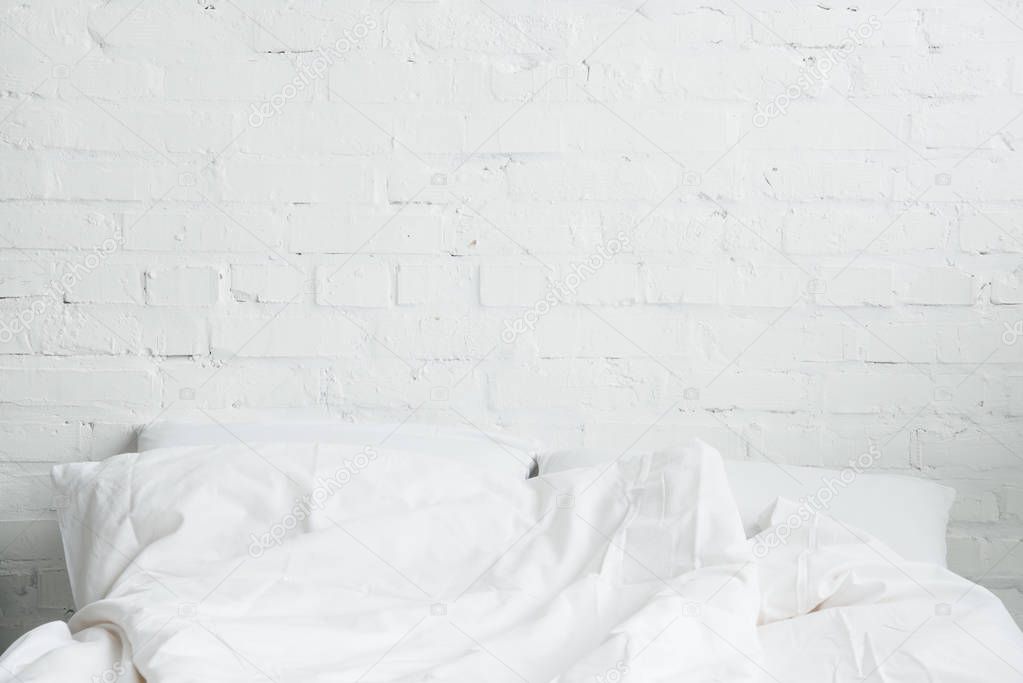 Empty and cozy bed with white pillows and blanket 