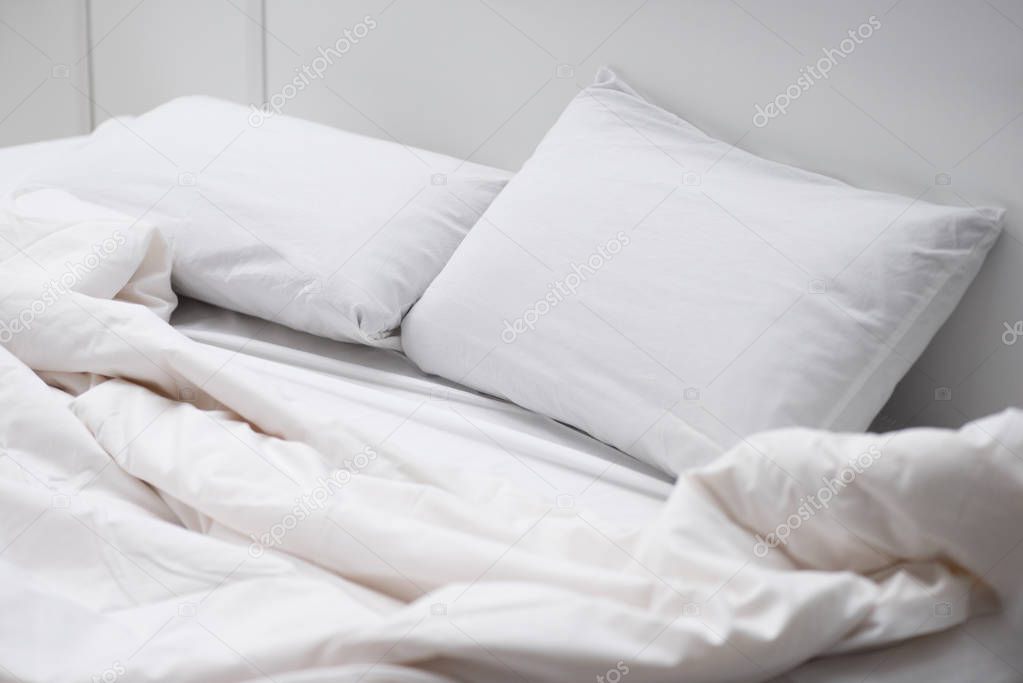 empty bed with white pillows and blanket 