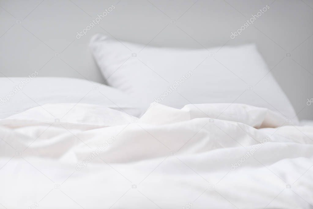 selective focus of empty bed with white pillows and blanket 