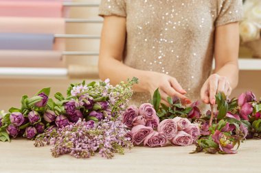 cropped view of florist making bouquet of tulips, peonies and lilac clipart