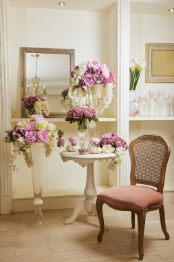 Interior of room with chair, mirror, bouquets in glass vases clipart
