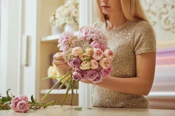 ワークスペースで牡丹とバラの花束を作る花屋の選択と集中 — ストック写真