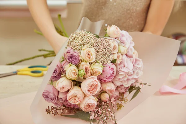 ワークスペースでバラとシャクヤクの花束をラッピングの花屋 — ストック写真