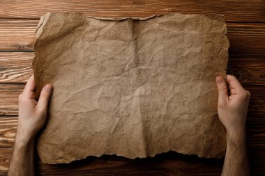 cropped view of man holding old parchment sheet in hands  clipart