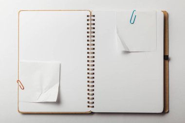 açılan defter ile yapışkan notlar ve ataç üstten görünüm beyaz arka plan üzerinde