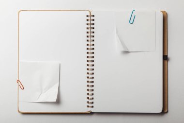 top view of opened notebook with sticky notes and paper clips on white background clipart