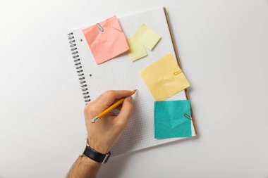 cropped view of man writing on blank squared sheet near crumpled paper sticks on white background  clipart