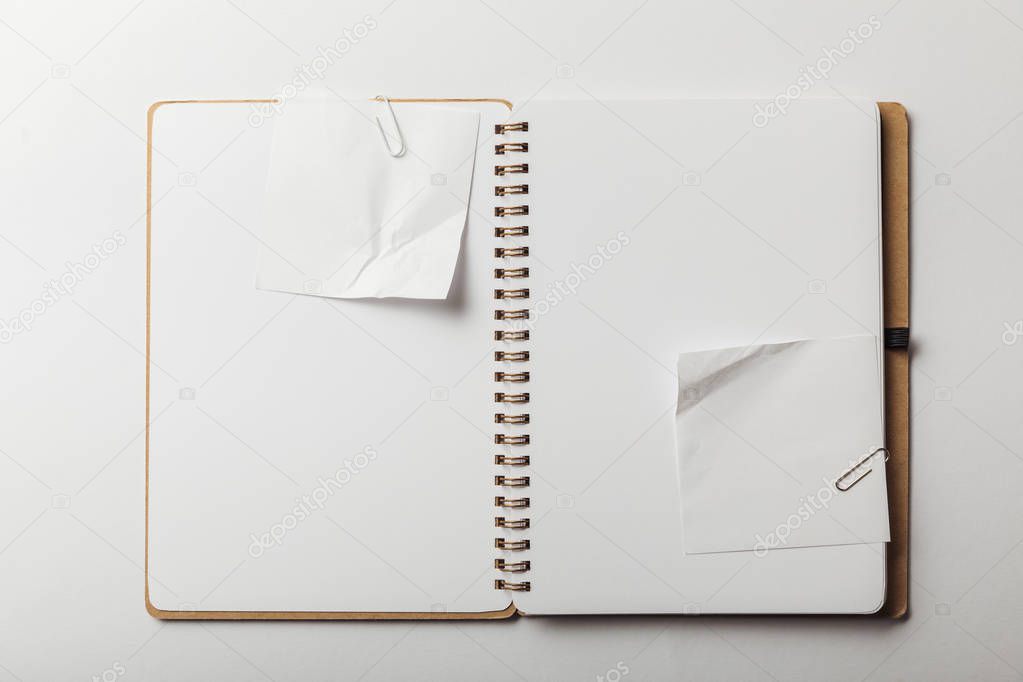 top view of notebook with white sticky notes and paper clips on white background