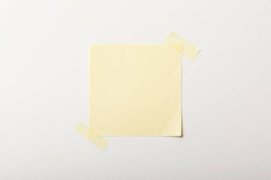 Beyaz arka plan üzerinde yapışkan bant ile sarı boş kağıt