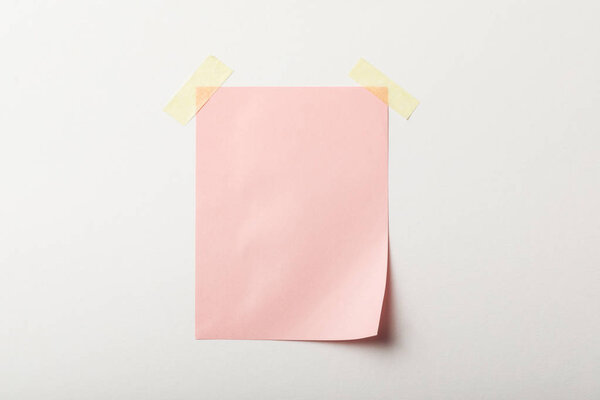 pink blank paper with sticky tape on white background
