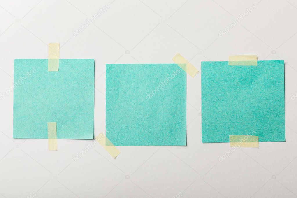 turquoise blank papers with sticky tape on white background