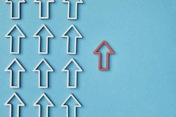 top view of vertical rows with white pointers near red arrow on blue background