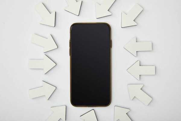 top view of smartphone in ellipse with white pointers on grey background