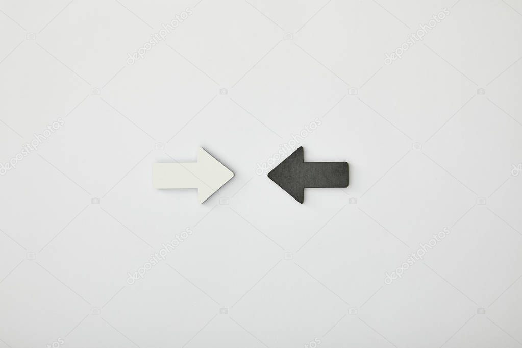 top view of white arrow opposite black pointer on grey background