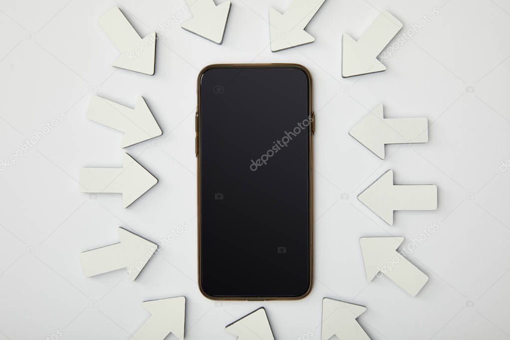 top view of smartphone in ellipse with white pointers on grey background