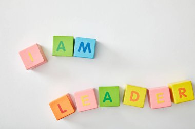 top view of i am leader lettering made of multicolored cubes on white background clipart