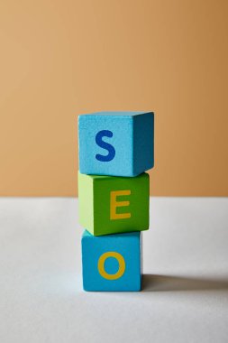 Beyaz masa ve bej renkli arka plan üzerinde renkli küpler SEO yazı yapılmış