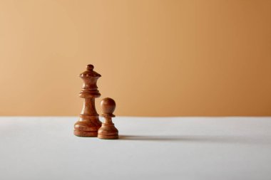 Beyaz masa ve bej renkli arka plan üzerinde ahşap Kraliçe ve piyon adet