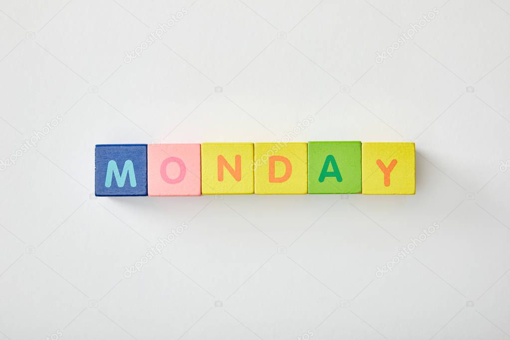 top view of monday lettering made of multicolored cubes on white background