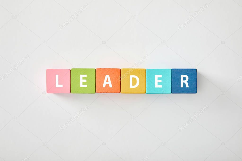 top view of leader lettering made of multicolored blocks on grey background