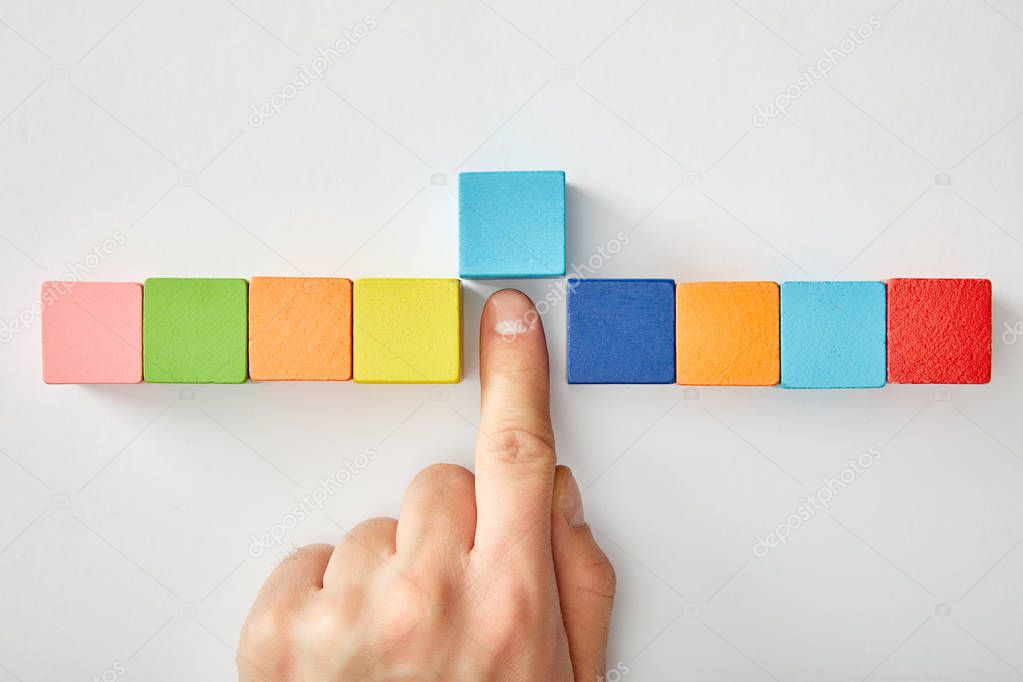 cropped view of male hand with multicolored cubes on grey background