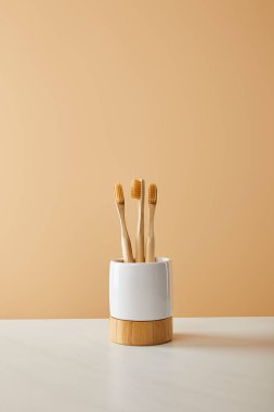 Bambu diş fırçası tutucu beyaz masa ve bej renkli arka plan üzerinde