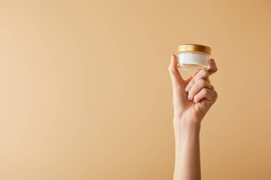 kozmetik krem bej renkli arka plan üzerinde tutan el görünümünü kırpılmış