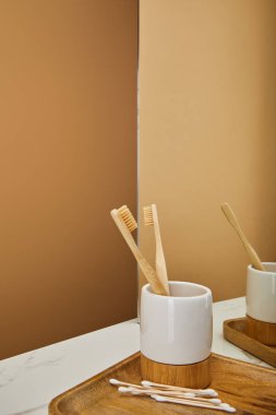 Bambu diş fırçası tutucu, kulak sopa ve beyaz mermer masa ve bej arka planı yansıtmadaki kurula