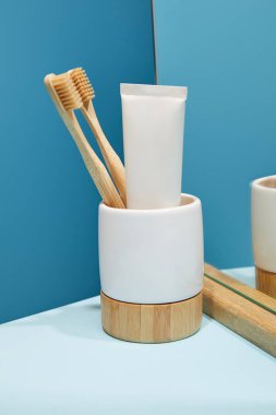 Bambu diş fırçası, diş macunu tüpü ve tablo ve mavi arka planı yansıtmadaki ile sahibi