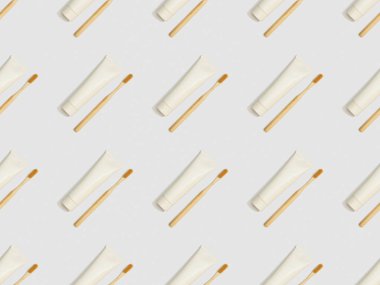 diagonally located toothbrushes and toothpaste in tubes on grey background, seamless background pattern clipart