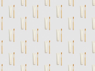 vertically located bamboo toothbrushes and toothpaste in tubes on grey background, seamless background pattern clipart