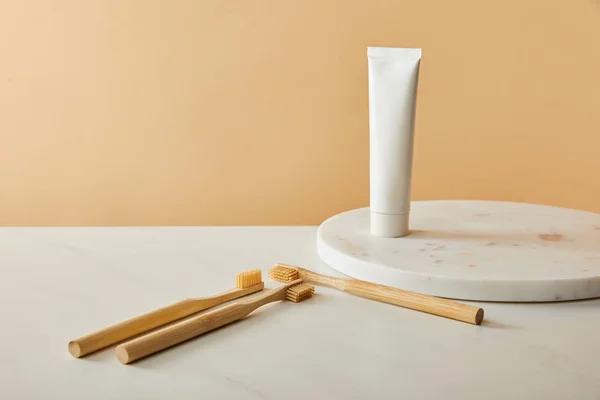 大理石圆板与牙膏在管和竹子牙刷在白色桌子和米色背景 — 图库照片