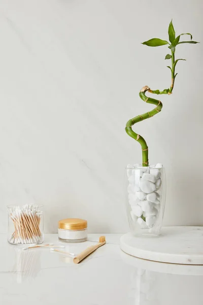 耳朵棍子在玻璃 化妆品奶油和牙刷附近竹茎在花瓶在白色大理石背景 — 图库照片