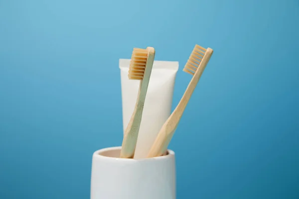 Halter Mit Zahnpasta Tube Und Bambuszahnbürsten Auf Blauem Hintergrund — Stockfoto
