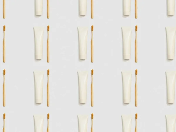 bamboo toothbrushes and toothpaste in tubes on grey background, seamless background pattern