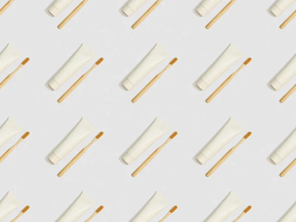 diagonally located toothbrushes and toothpaste in tubes on grey background, seamless background pattern