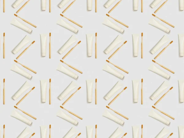 bamboo toothbrushes and toothpaste in tubes in different directions on grey background, seamless background pattern