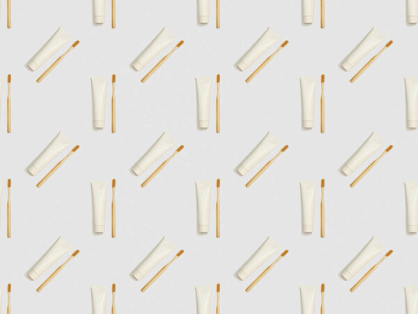 bamboo toothbrushes and toothpaste in different directions on grey background, seamless background pattern