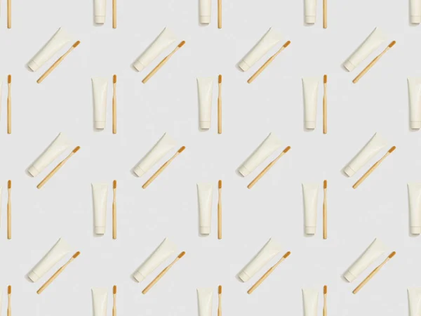 bamboo toothbrushes and toothpaste in different directions on grey background, seamless background pattern