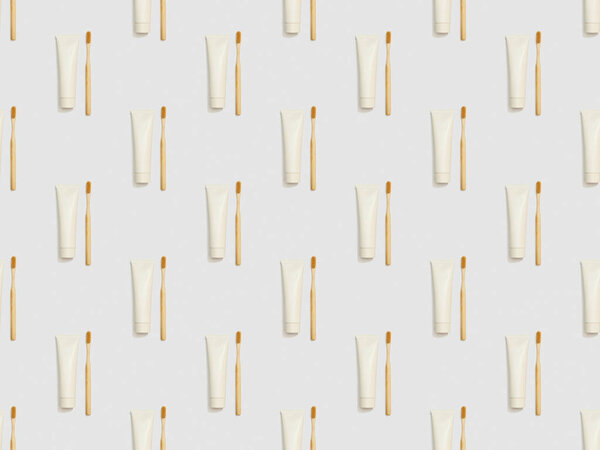 vertically located bamboo toothbrushes and toothpaste in tubes on grey background, seamless background pattern