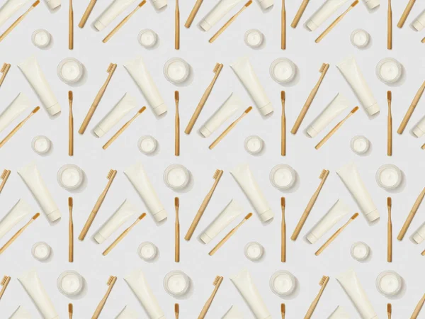 bamboo toothbrushes, toothpaste in tube in different directions and cosmetic cream on grey background, seamless background pattern