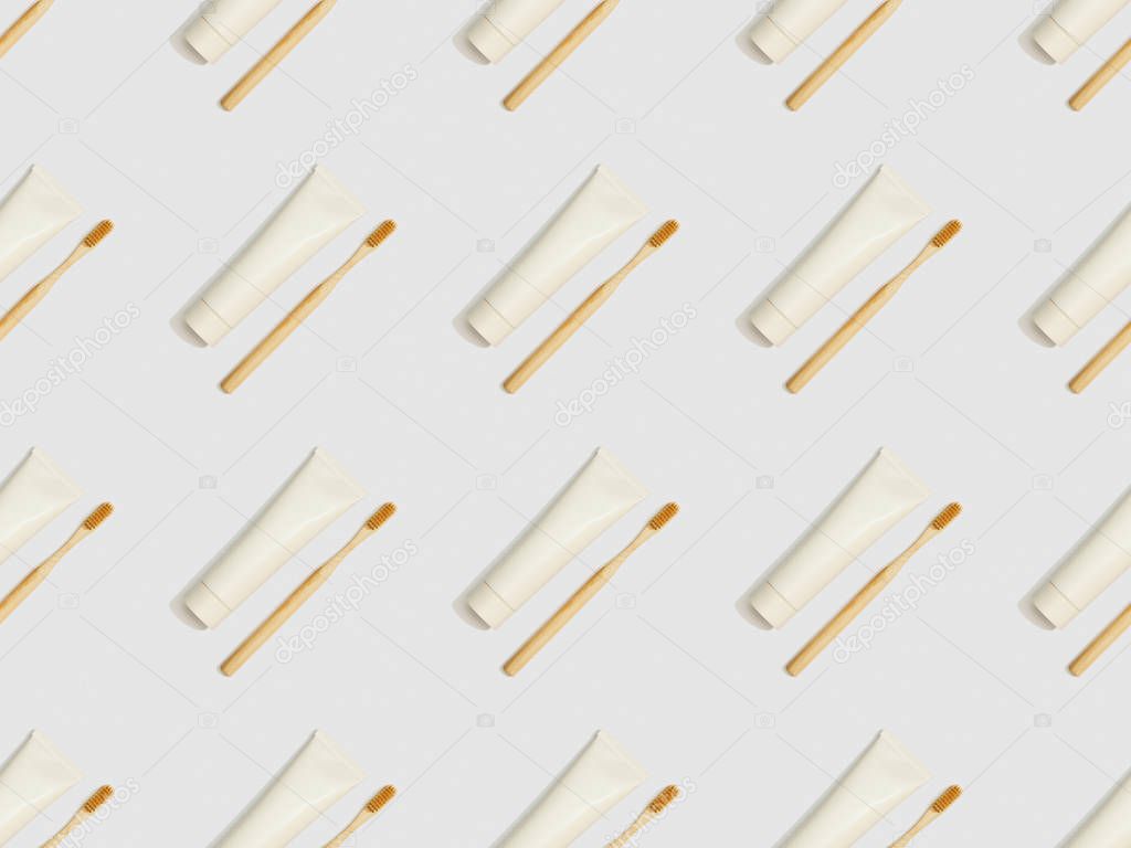 diagonally located toothbrushes and toothpaste in tubes on grey background, seamless background pattern