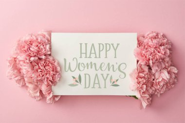 top view of greeting card with happy womens day lettering and pink carnations on pink background clipart