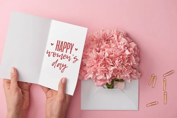 카네이션 분홍색 배경에 봉투에 가까운 인사말 카드를 여자의 보기를 — 스톡 사진