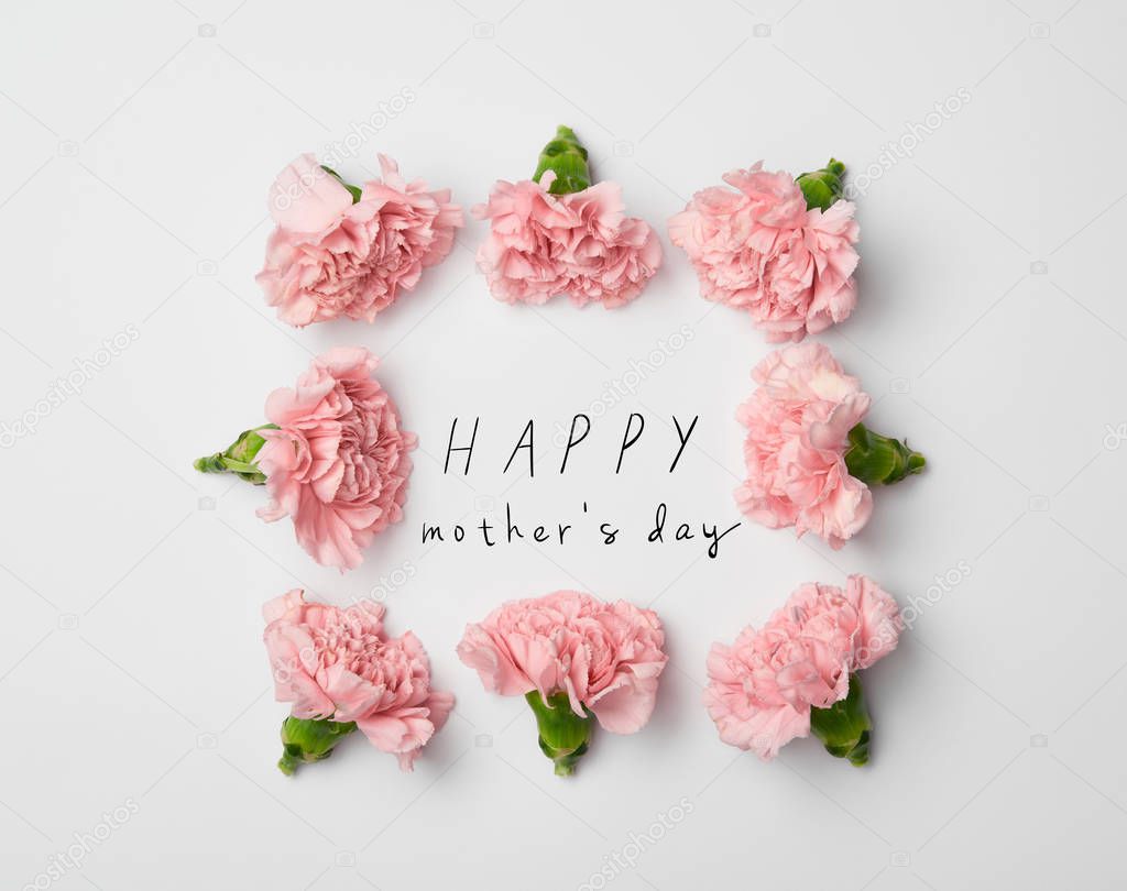 top view of floral frame made of pink carnations on white background with happy mothers day lettering