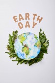 top view of fresh green fern leaves with paper letters and planet picture isolated on grey background, earth day concept