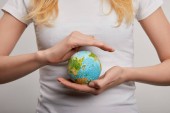 woman holding planet model on grey background, earth day concept