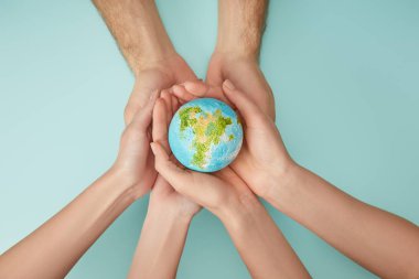 top view of man and woman holding planet model on turquoise background, earth day concept clipart